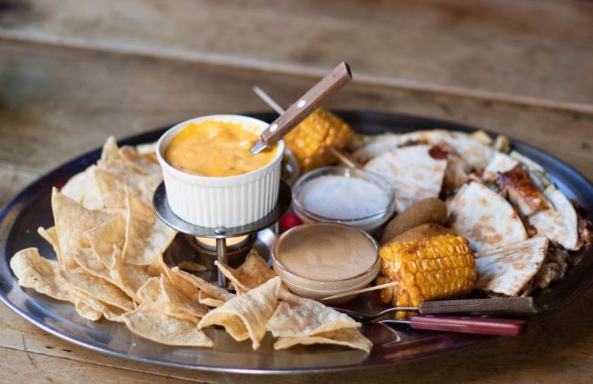 Mexican platter featuring cheese dip, corn, quesadillas, and chips.